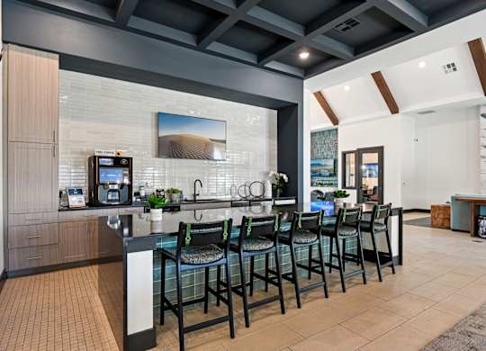 A modern kitchen with a black countertop and chairs.
