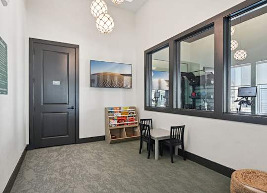 A room with a black door, a chair, a table, and a painting on the wall.