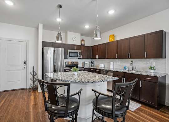 A kitchen with a granite countertop and a stainless steel refrigerator.