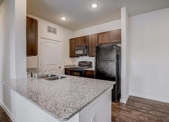 Kitchen with granite peninsula, dark cabinets, and open dining area.