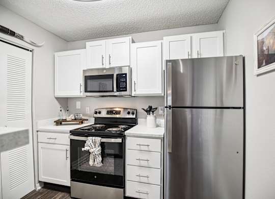 A kitchen with white cabinets and a stainless steel refrigerator.