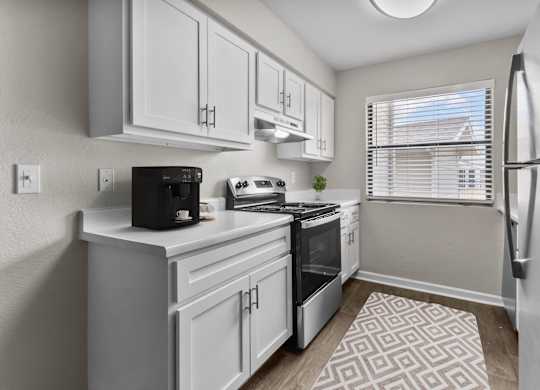 an open kitchen with white cabinets and a window and a refrigerator