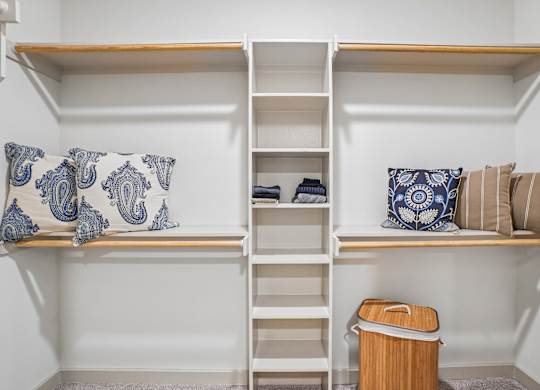 A white shelving unit with a blue and white pillow on it.