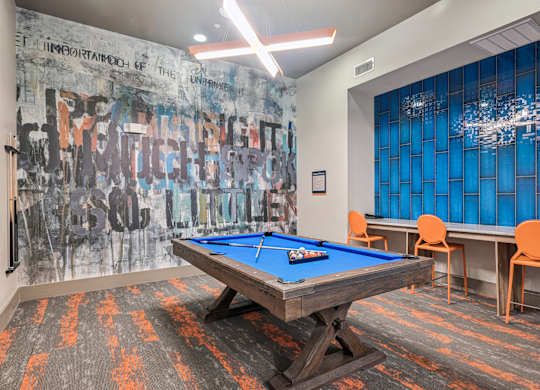 A pool table in a room with a graffiti wall.