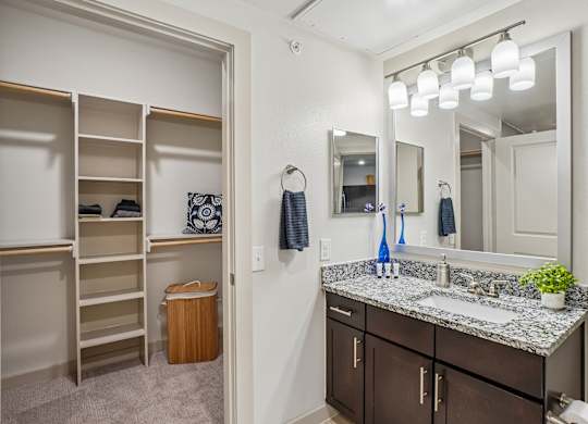 A bathroom with a large mirror, a sink, and a cabinet with shelves.