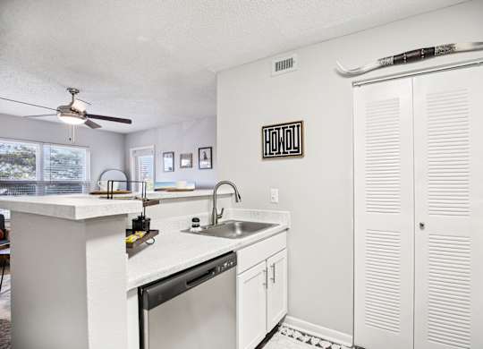 A kitchen with white cabinets and a black fridge.
