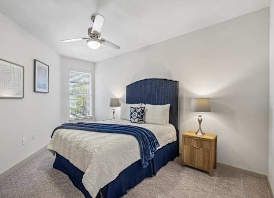 A bedroom with a bed, nightstand, and two lamps.