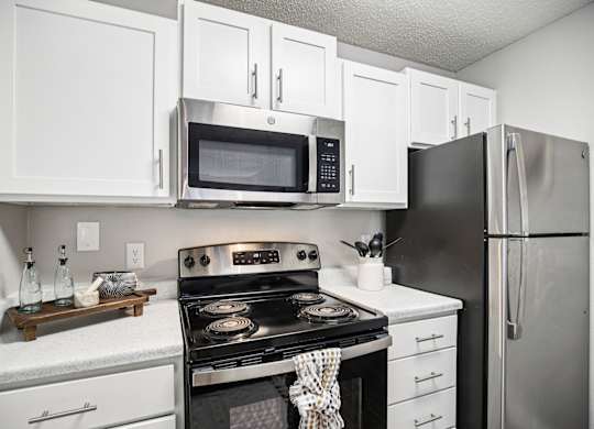 A modern kitchen with white cabinets and stainless steel appliances.