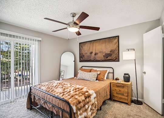A bedroom with a bed, nightstand, and a painting on the wall.