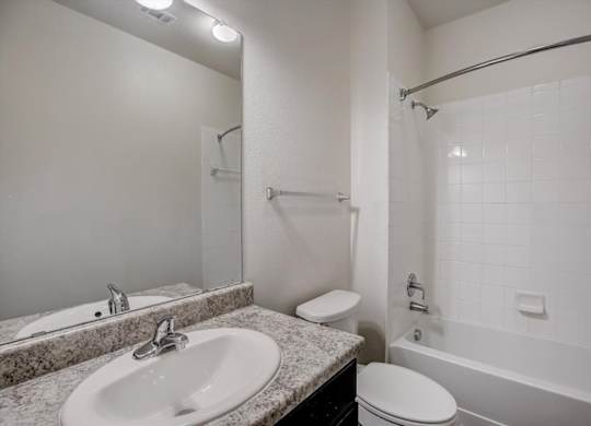 Bathroom with granite vanity, framed mirror, and tub-shower combo.