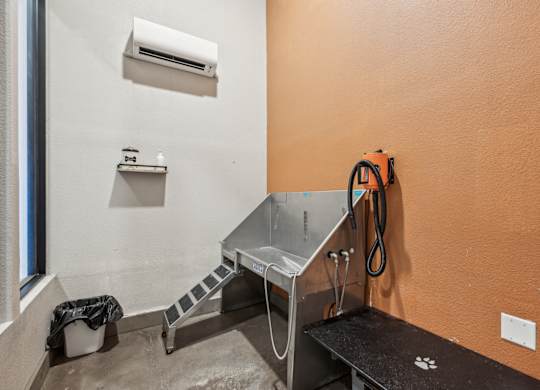 A room with orange walls has a table, a bench, and a window.
