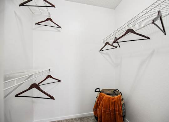 A white wall with clothes hangers and a bag.