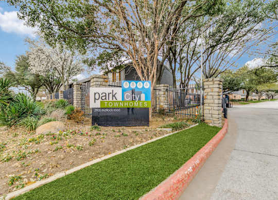 A sign for Park City Townhomes stands in front of a gated entrance.