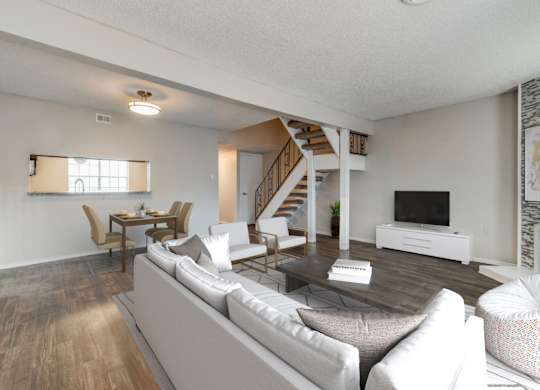 A living room with a grey sofa and a wooden staircase.