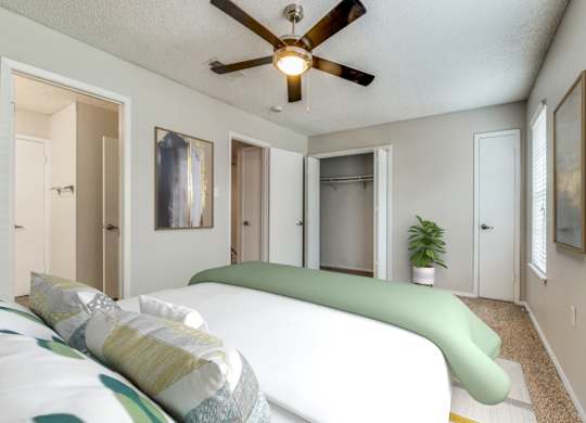 A bedroom with a bed and a ceiling fan.