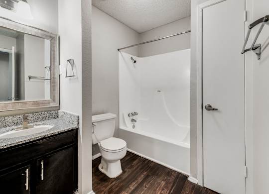 A white toilet sits next to a white bathtub in a bathroom.