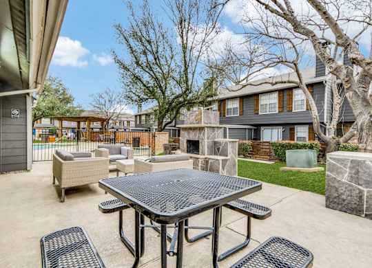 A patio with a table and chairs is surrounded by trees and houses.