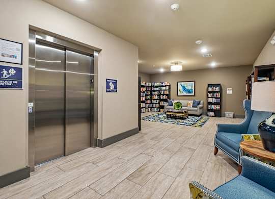 A hallway with a blue couch, a bookshelf, and a coffee table.