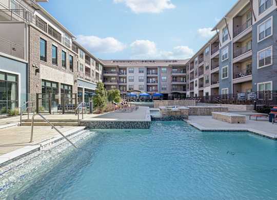 A swimming pool in a residential area surrounded by apartment buildings.