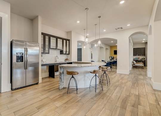 A kitchen with a bar and stools in the middle of the room.