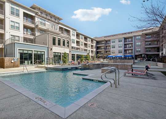 A swimming pool in front of apartment buildings.