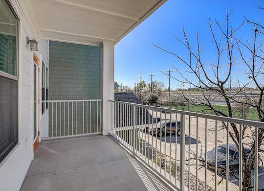 Private covered balcony with shaded concrete patio and metal railing.