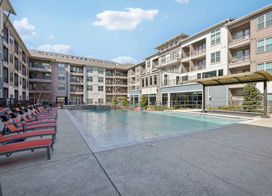 A large swimming pool is surrounded by apartment buildings.