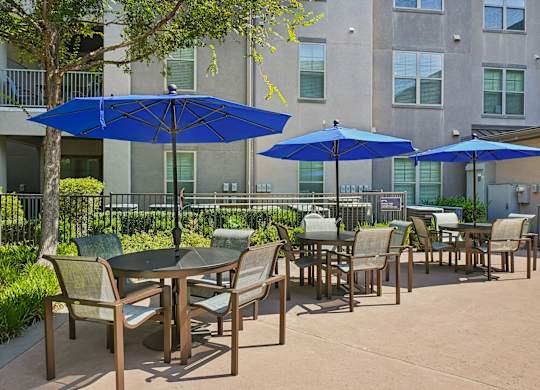 A patio with tables and chairs and umbrellas.