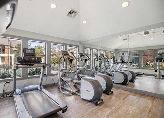 A gym with treadmills, elliptical machines and other exercise equipment.