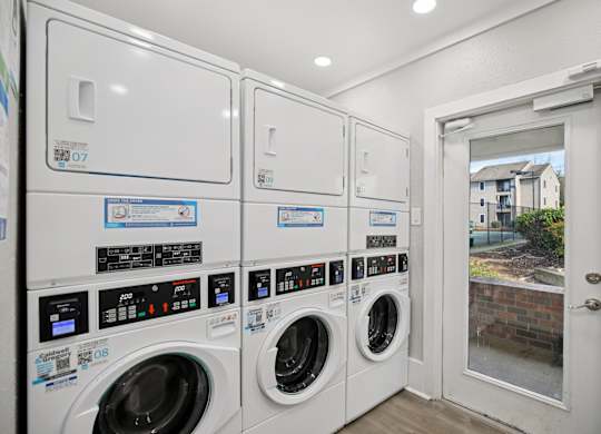 A row of washing machines are lined up in a laundry room.