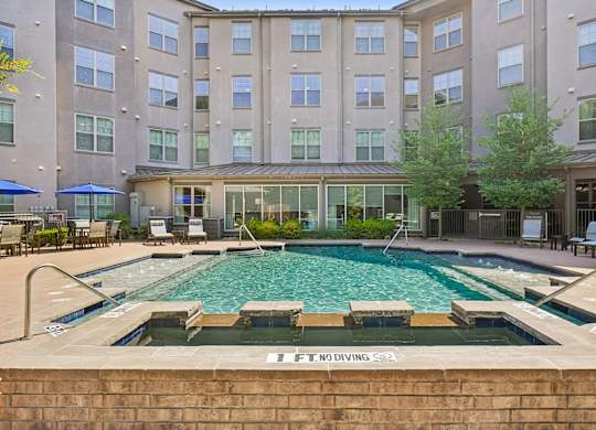 A large swimming pool in front of a building with a sign that says "No Diving".