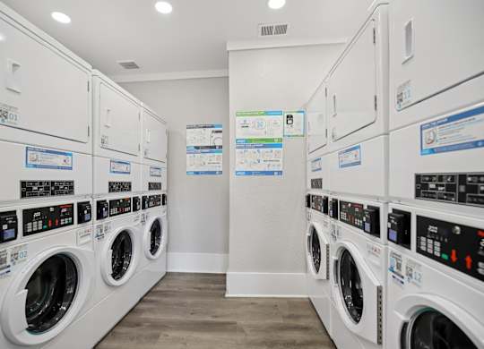 A row of white front load washing machines in a laundromat.