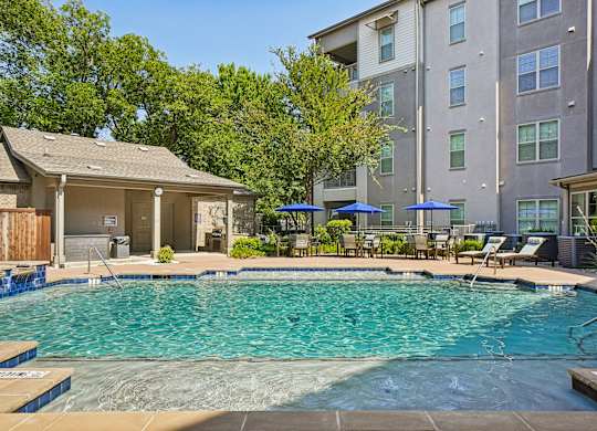 A swimming pool surrounded by a wooden deck and chairs.