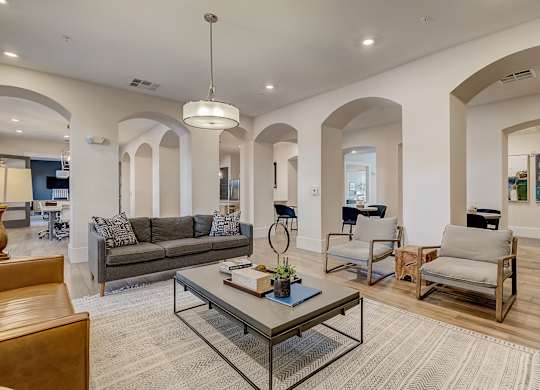 A modern living room with a grey couch, a glass coffee table, and a wooden chair.