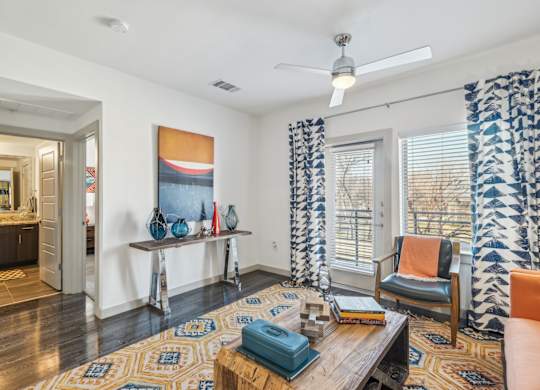 A living room with a rug, a chair, a table, and a painting on the wall.