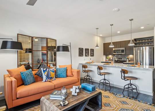 A modern living room with a kitchen in the background.