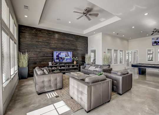 Clubhouse lounge with leather seating, large TV, and game room area.