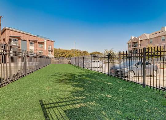 A sunny day at a residential area with houses, cars, and a green lawn.