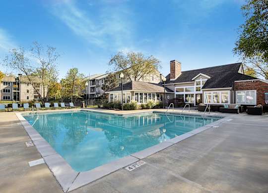 A large swimming pool in front of a building with a clear blue sky above.