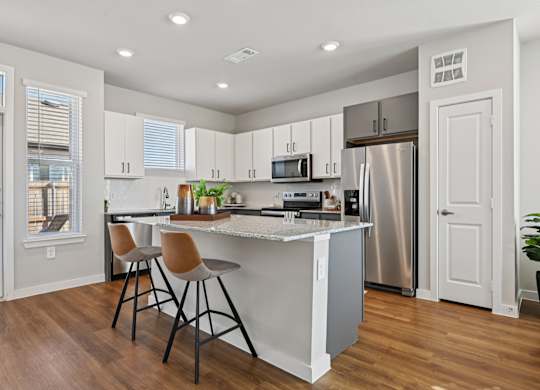 A kitchen with white cabinets and a wooden floor.