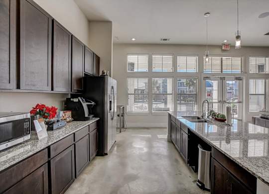 Clubhouse kitchen with long granite island, pendant lights, and window wall.