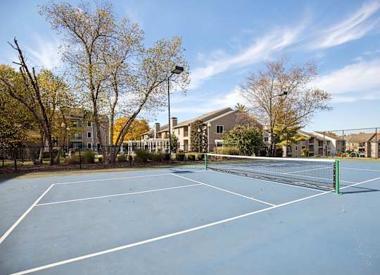 A tennis court surrounded by trees and buildings.