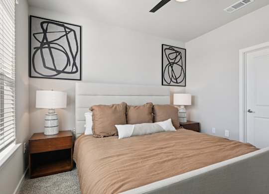 A bedroom with a bed, two lamps, and two wall art pieces.