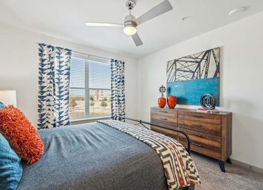 A bedroom with a bed, a dresser, and a painting on the wall.