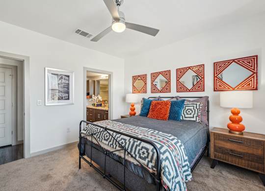 A bedroom with a bed, a dresser, and a ceiling fan.