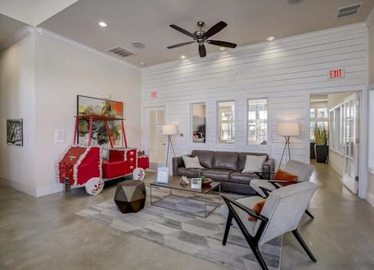 Clubhouse living area with sofa seating, area rug, and bright open layout.