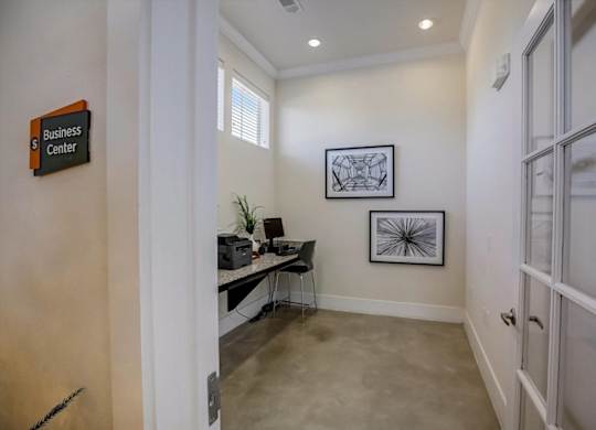 Compact business center room with workstation, glass door, and high windows.