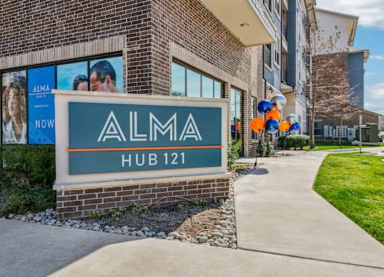 A sign for Alma Hub 121 is displayed in front of a building.