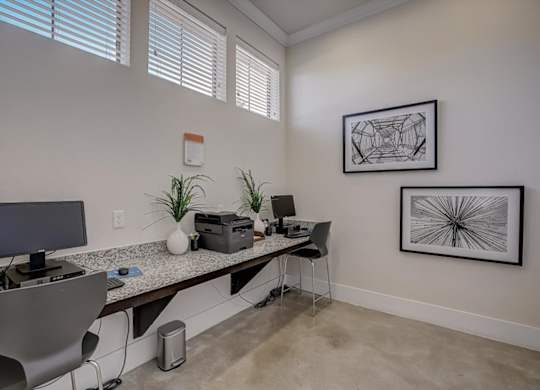 Business center workspace with computers, printer, and framed wall art.