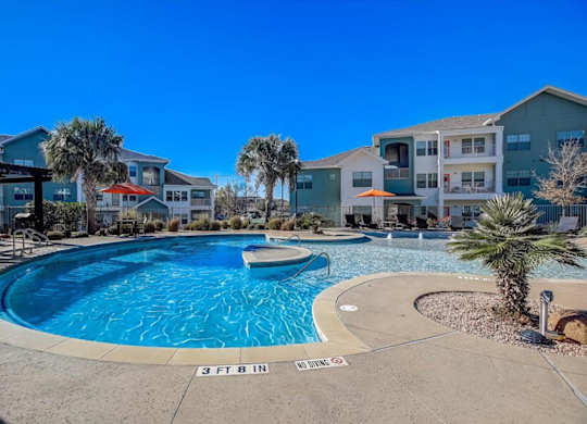 Curved pool in courtyard with palm trees and apartment buildings.
